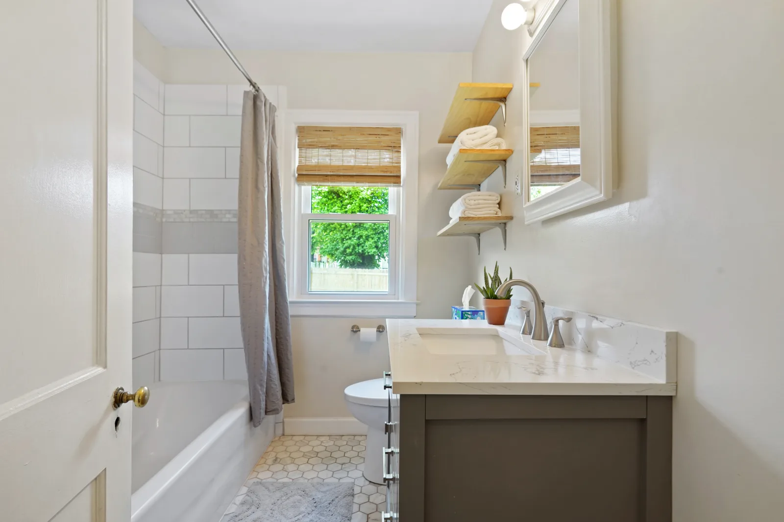 Updated bathroom with white subway tile, a quartz vanity, and open wood shelving in a Lexington home