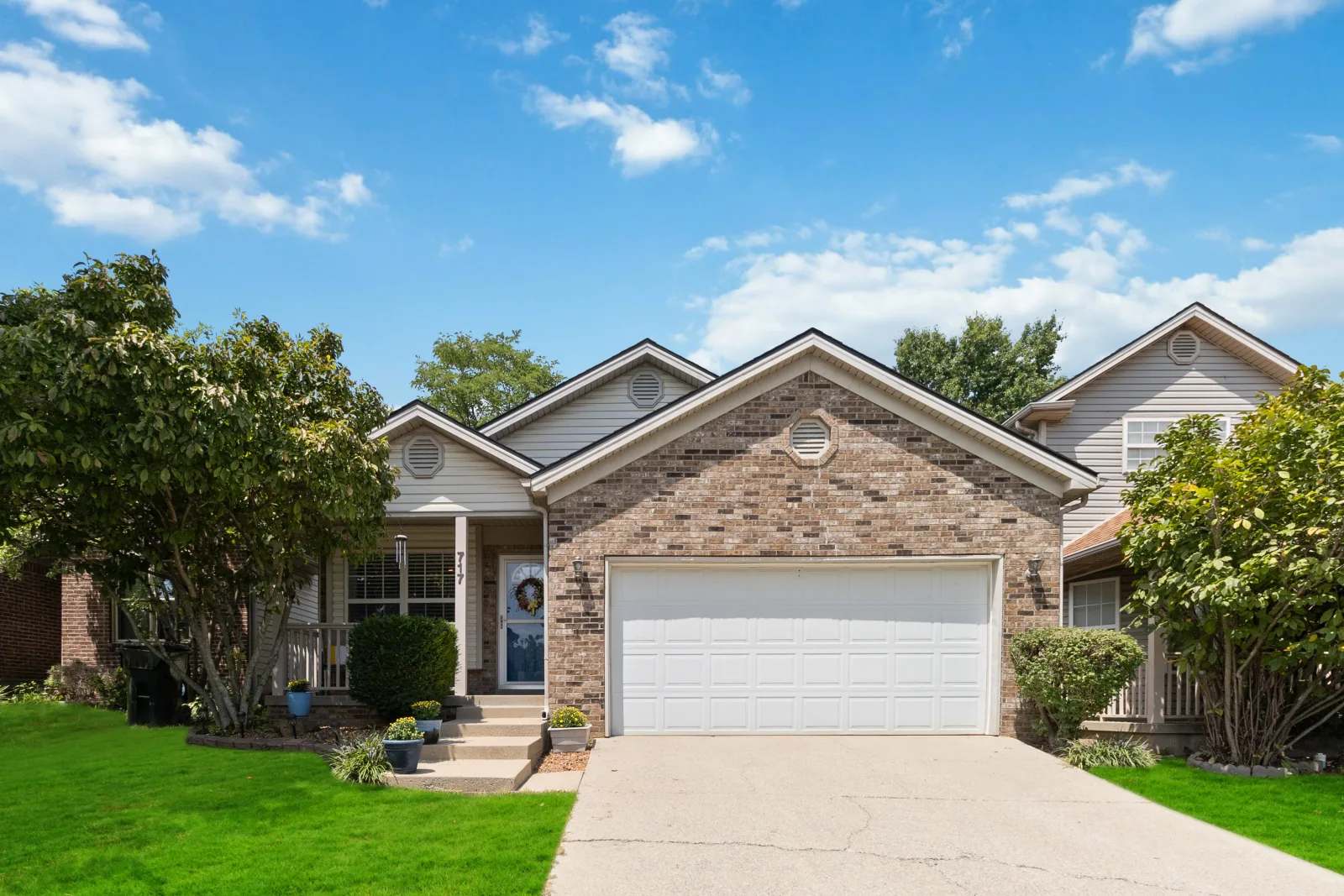 A brick ranch starter home with a two-car garage and green lawn on a sunny day in Lexington, Kentucky