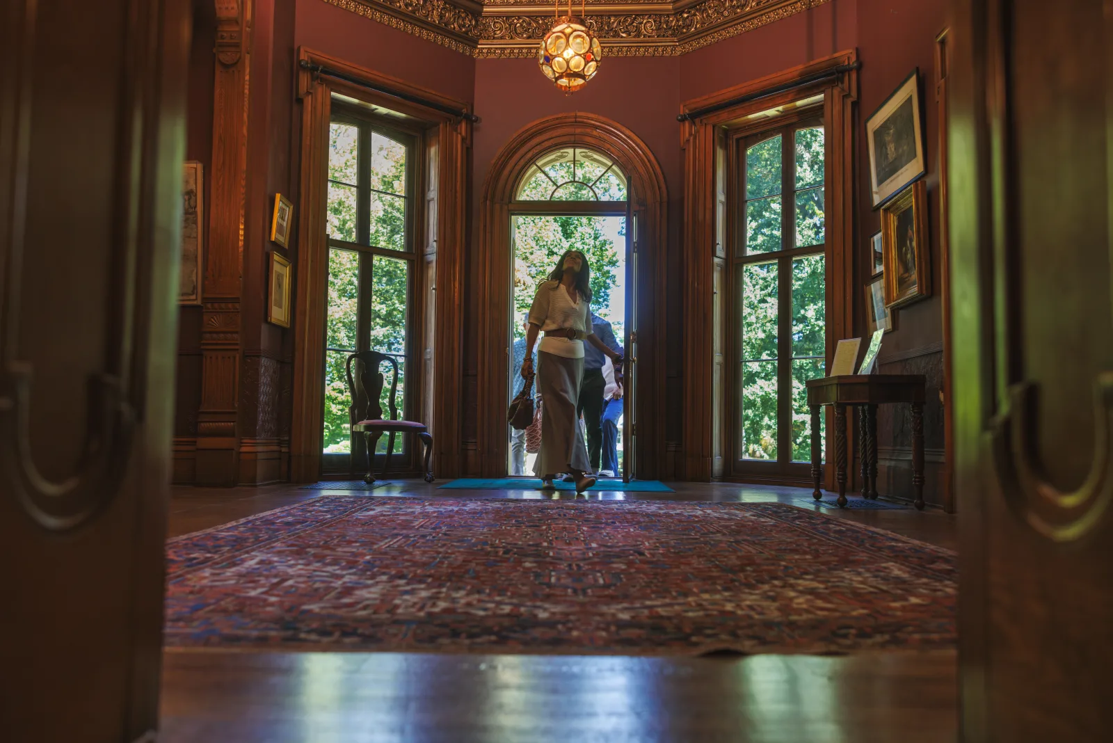 Ornate entry hall of a historic Lexington KY mansion with deep-red walls and dark wood paneling from the Athens of the West era