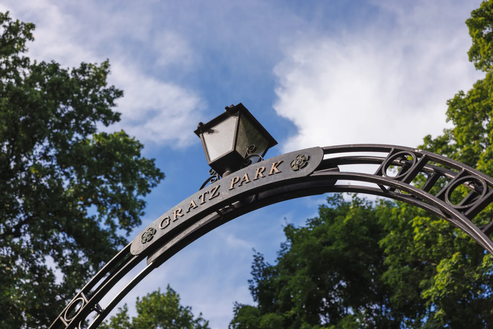 Wrought-iron Gratz Park entrance arch with its lantern against a blue sky in historic downtown Lexington KY