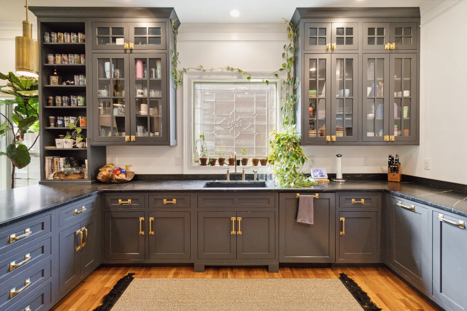 A renovated kitchen with charcoal cabinetry and gold hardware in a Lexington KY home