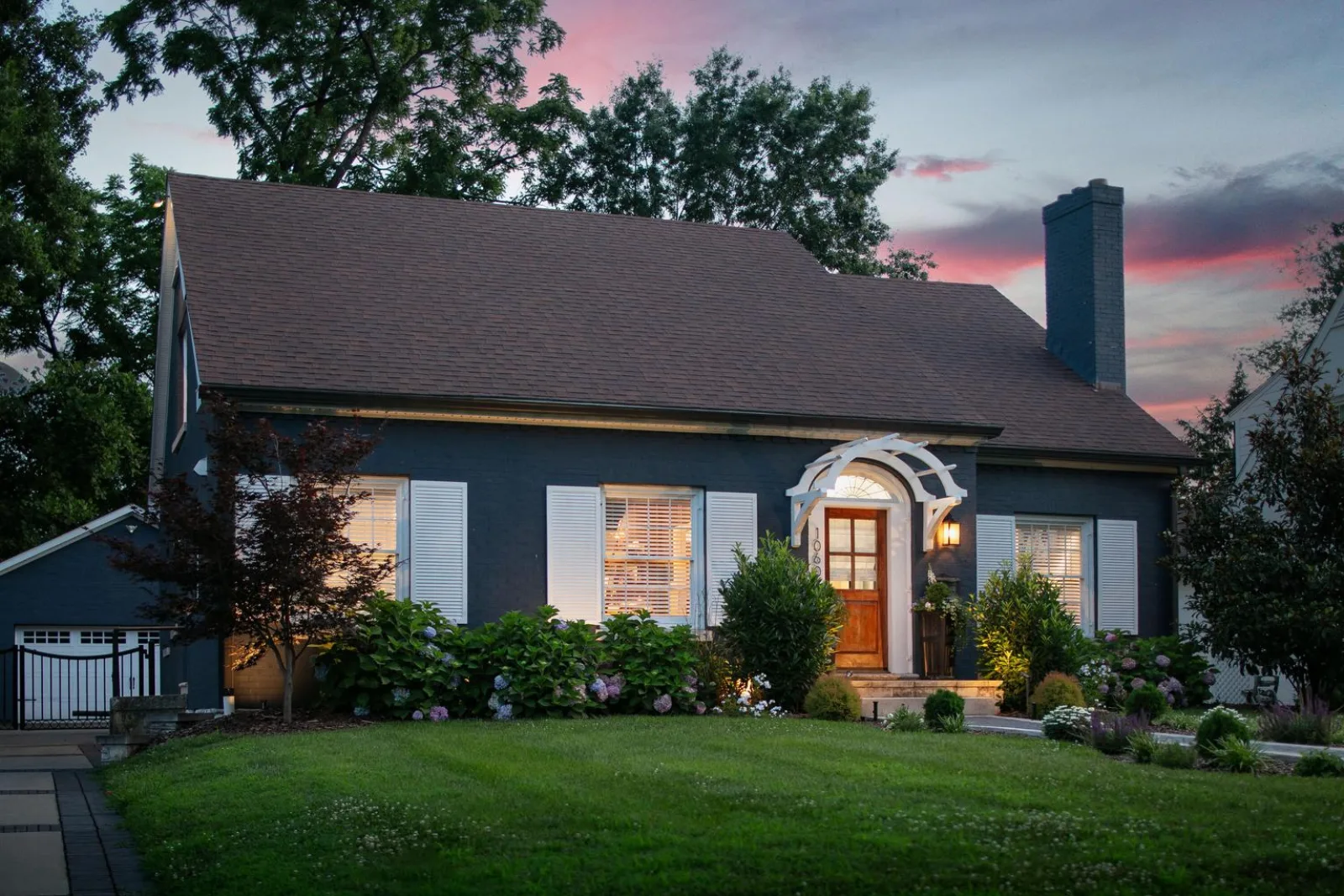 A charming navy-brick cottage with landscaped gardens at dusk in a Lexington KY neighborhood