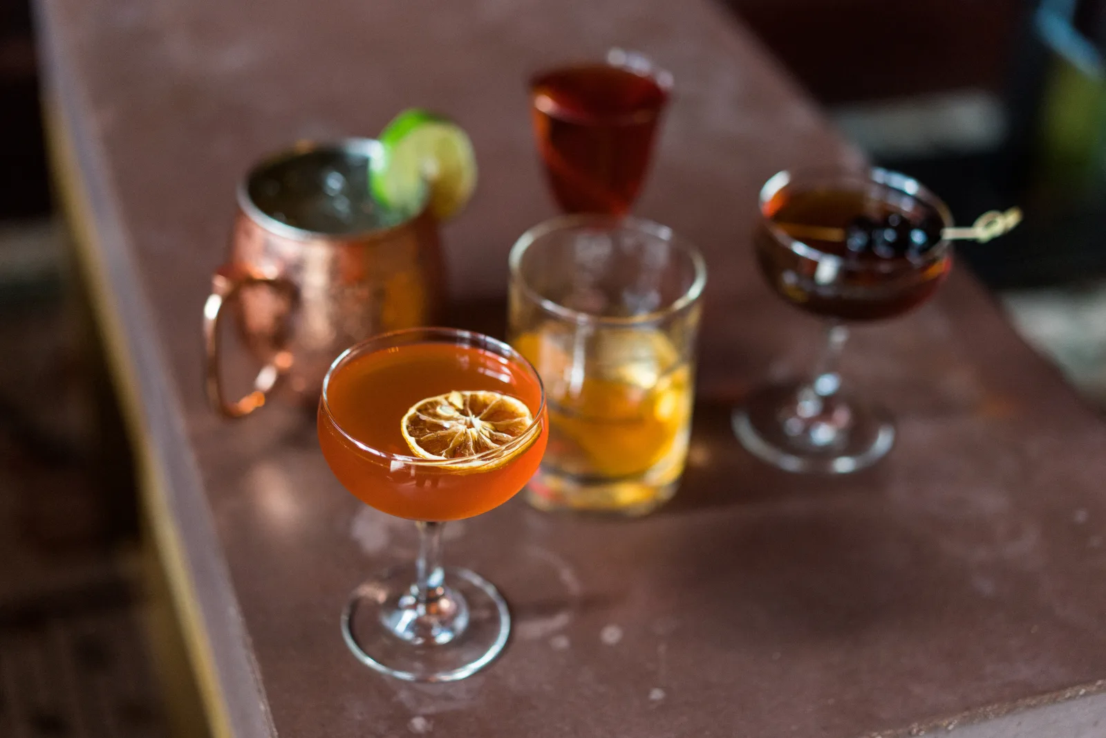 Craft cocktails lined up on a stone ledge at a Lexington bar