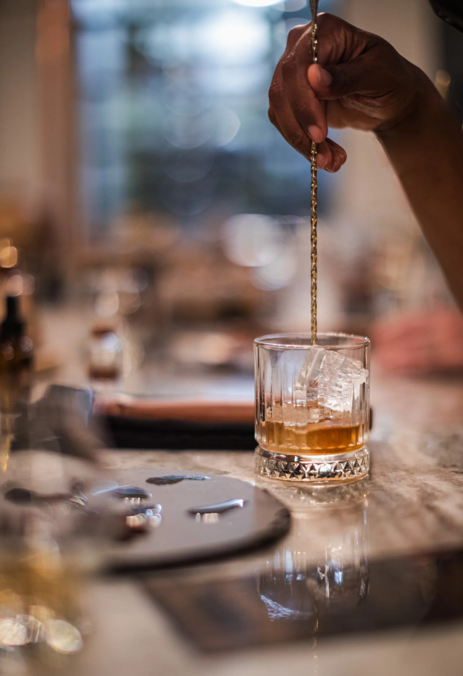 A bourbon cocktail being stirred over a large ice cube at a Lexington bar