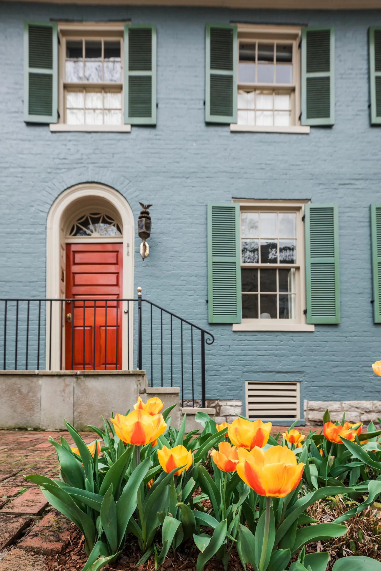 Historic slate-blue brick rowhouse with green shutters on a Lexington boutique street