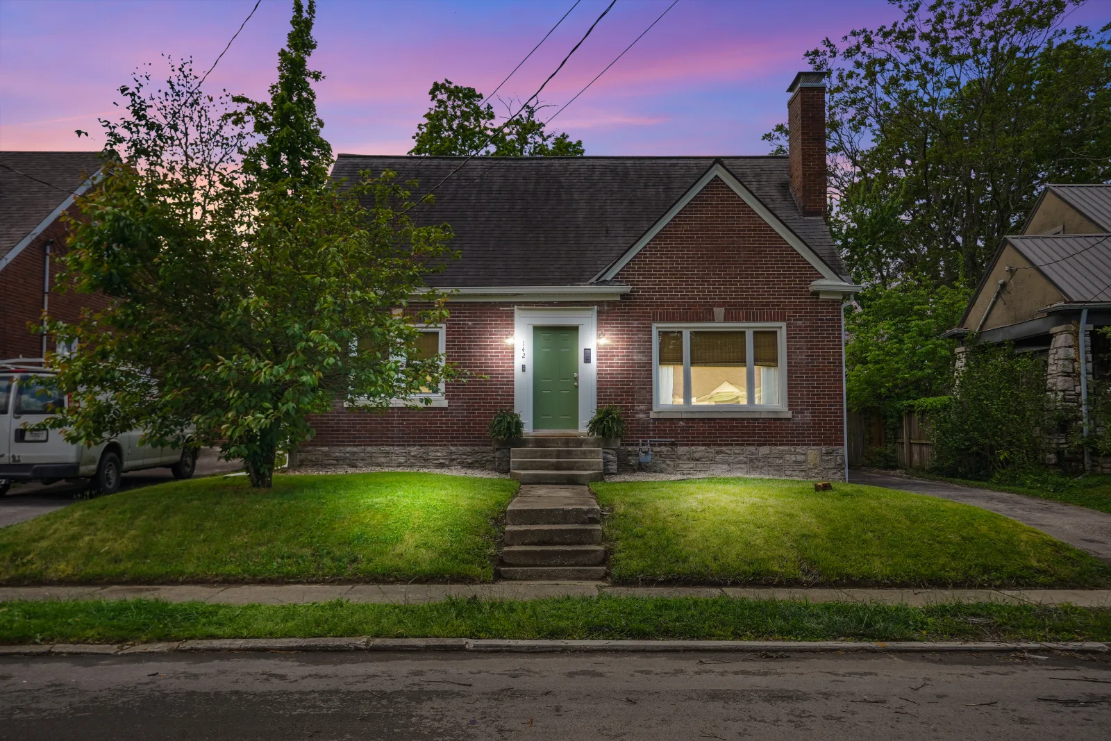 A renovated navy bungalow with a metal roof and covered porch in a Lexington KY neighborhood
